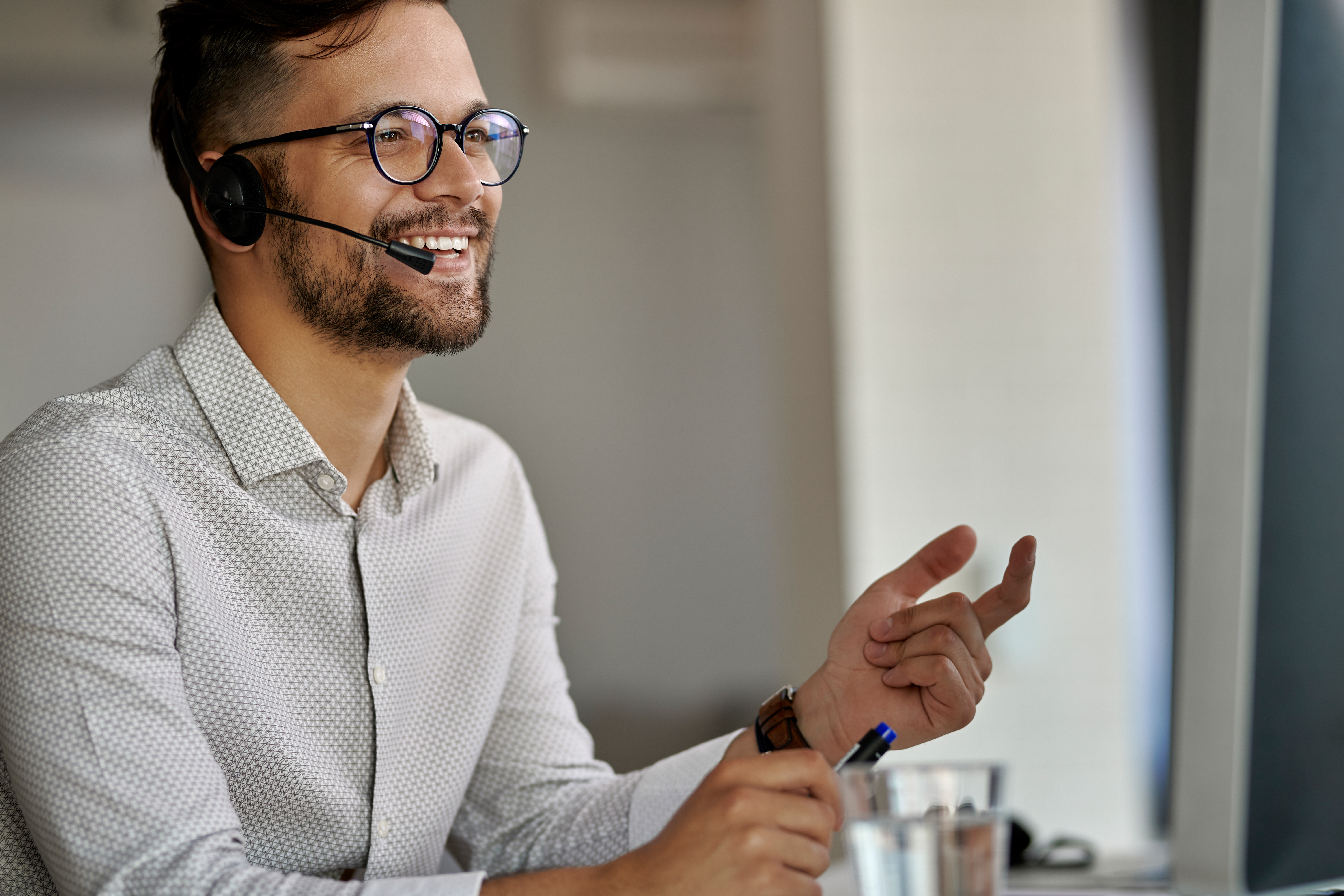 Man in white shirt talking into headset happily 