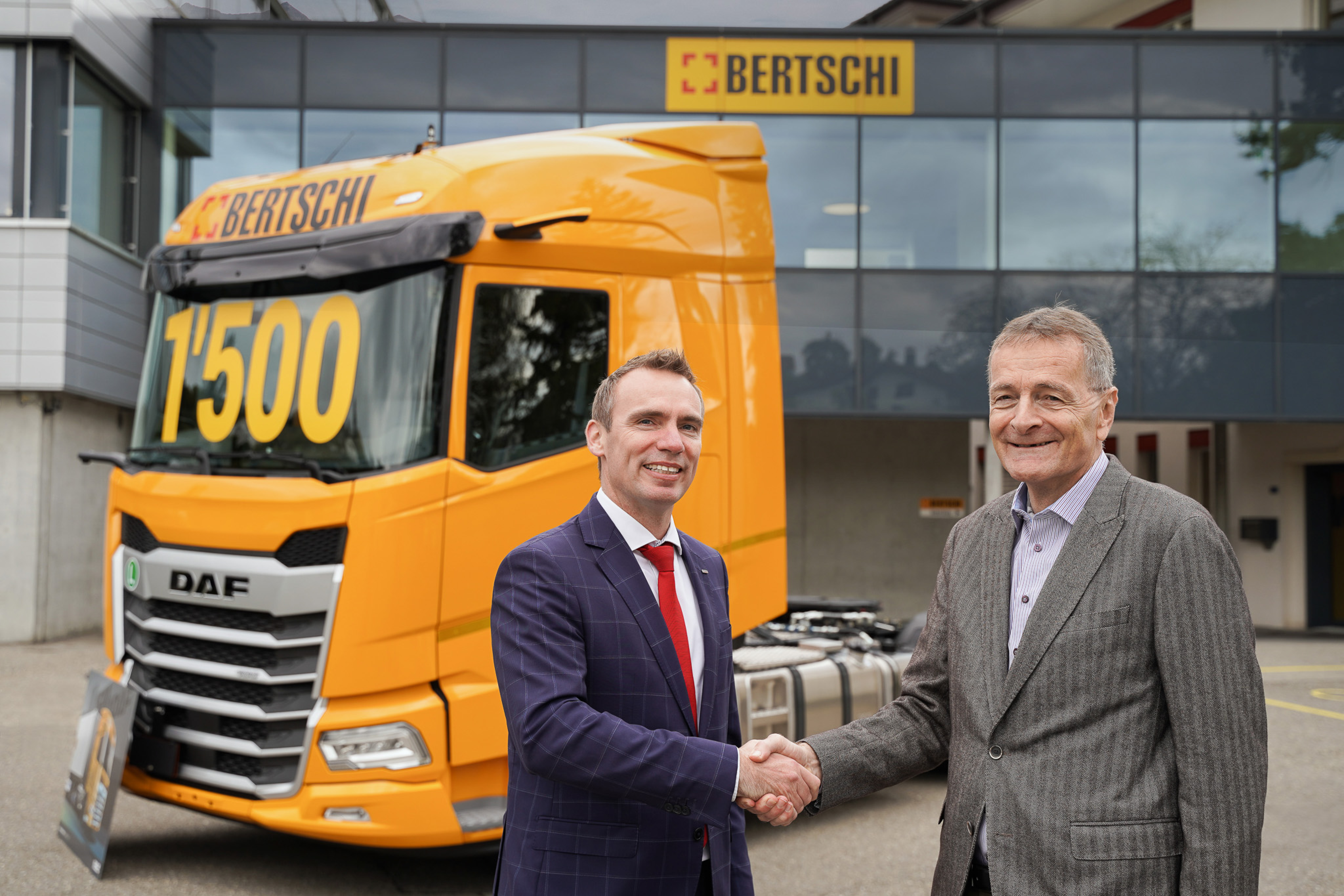 DAF and Bertschi executives shaking hands in front of a Bertschi truck with 1500 written on the windshield 