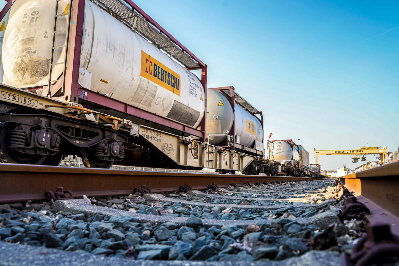 Stacked chemical containers at Bertschi Rotterdam ADR storage facility with safety signage visible
