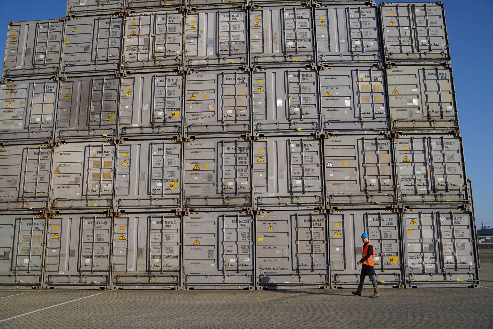 Stacked drybulk box chemical containers at Bertschi Rotterdam ADR storage facility with safety signage visible