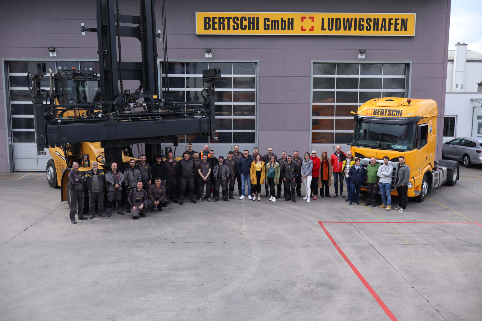 A group foto of the employees with a Truck and a Stack reacher