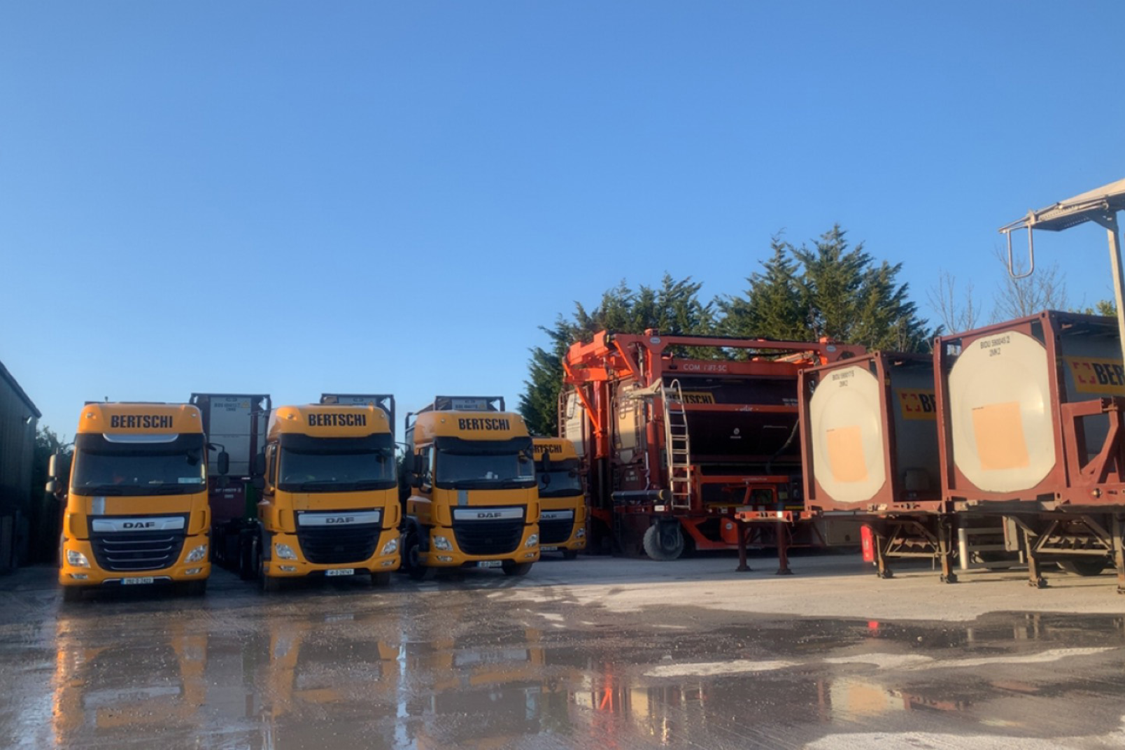 LKW's in a row next to each other with containers in the background