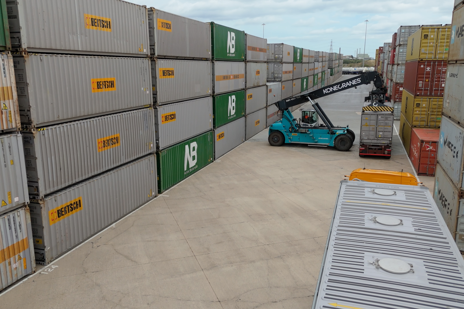 Containers stacked on top of each other and in a row with a stack reacher