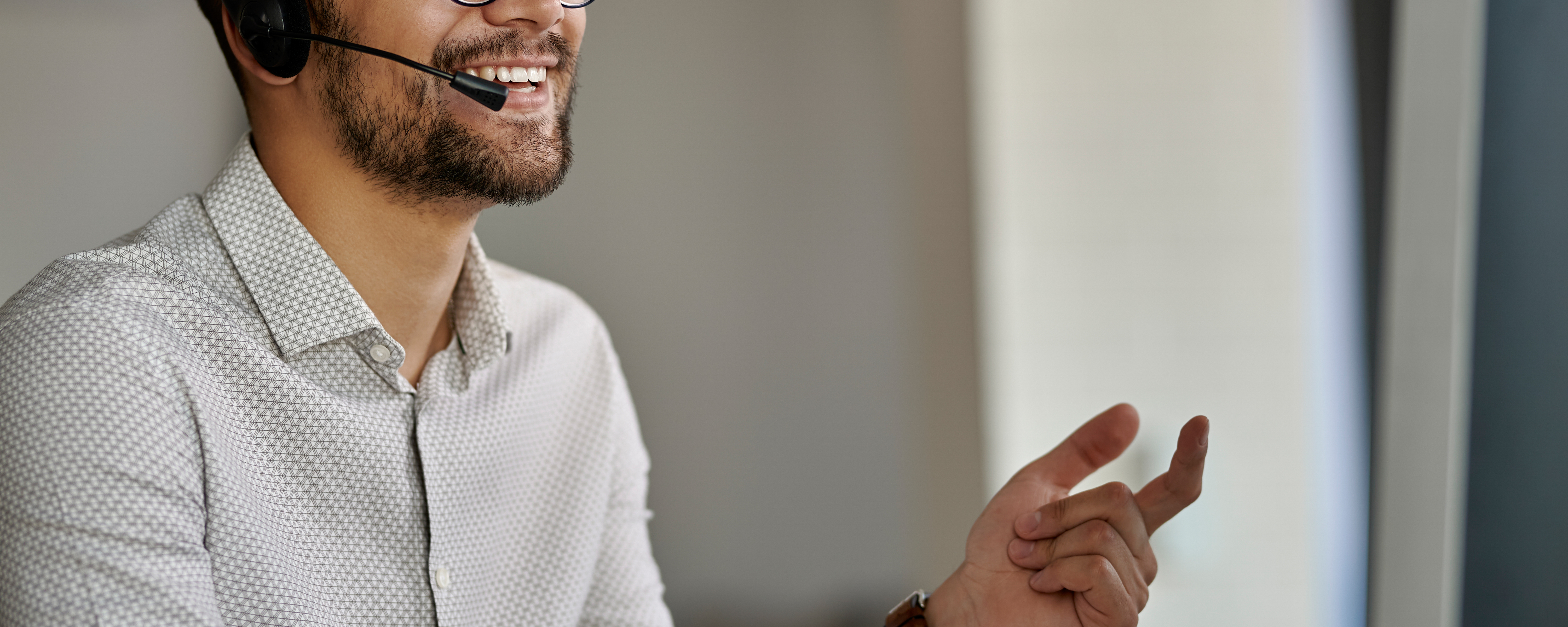 Man in white shirt talking into headset happily 