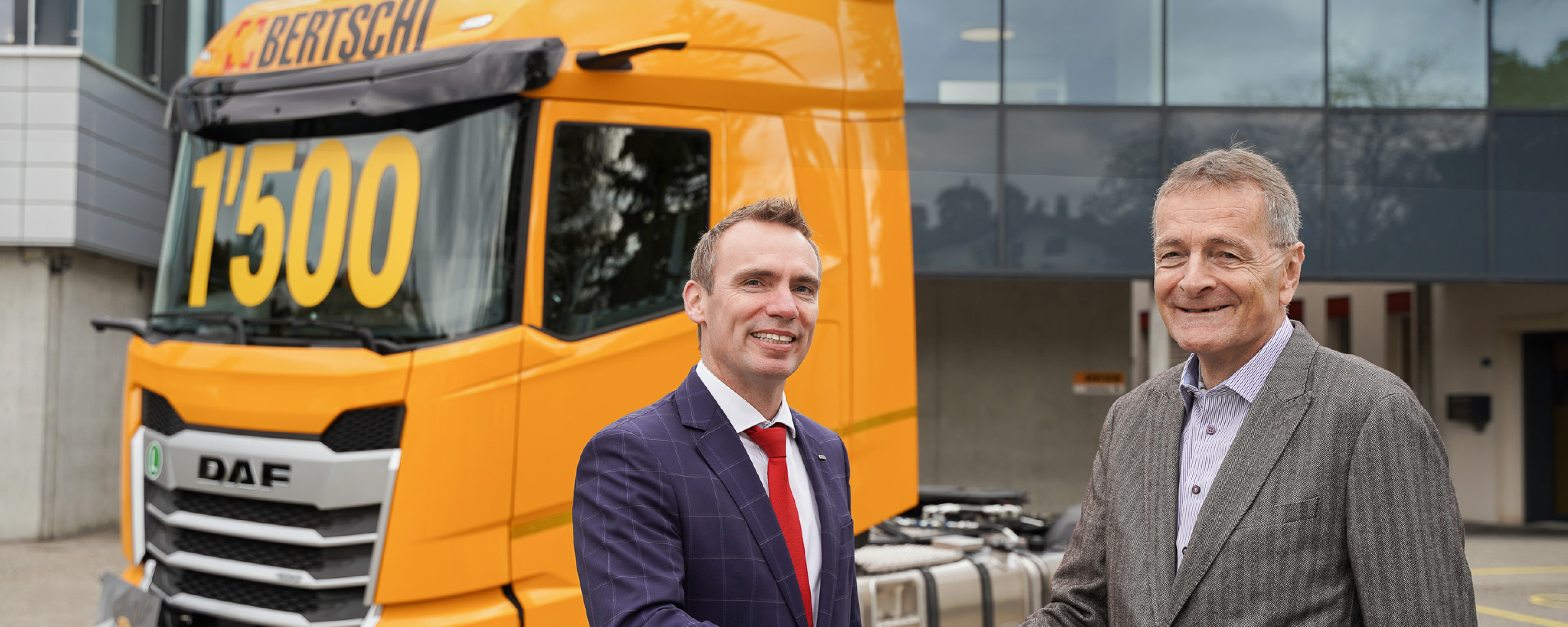 DAF and Bertschi executives shaking hands in front of a Bertschi truck with 1500 written on the windshield 
